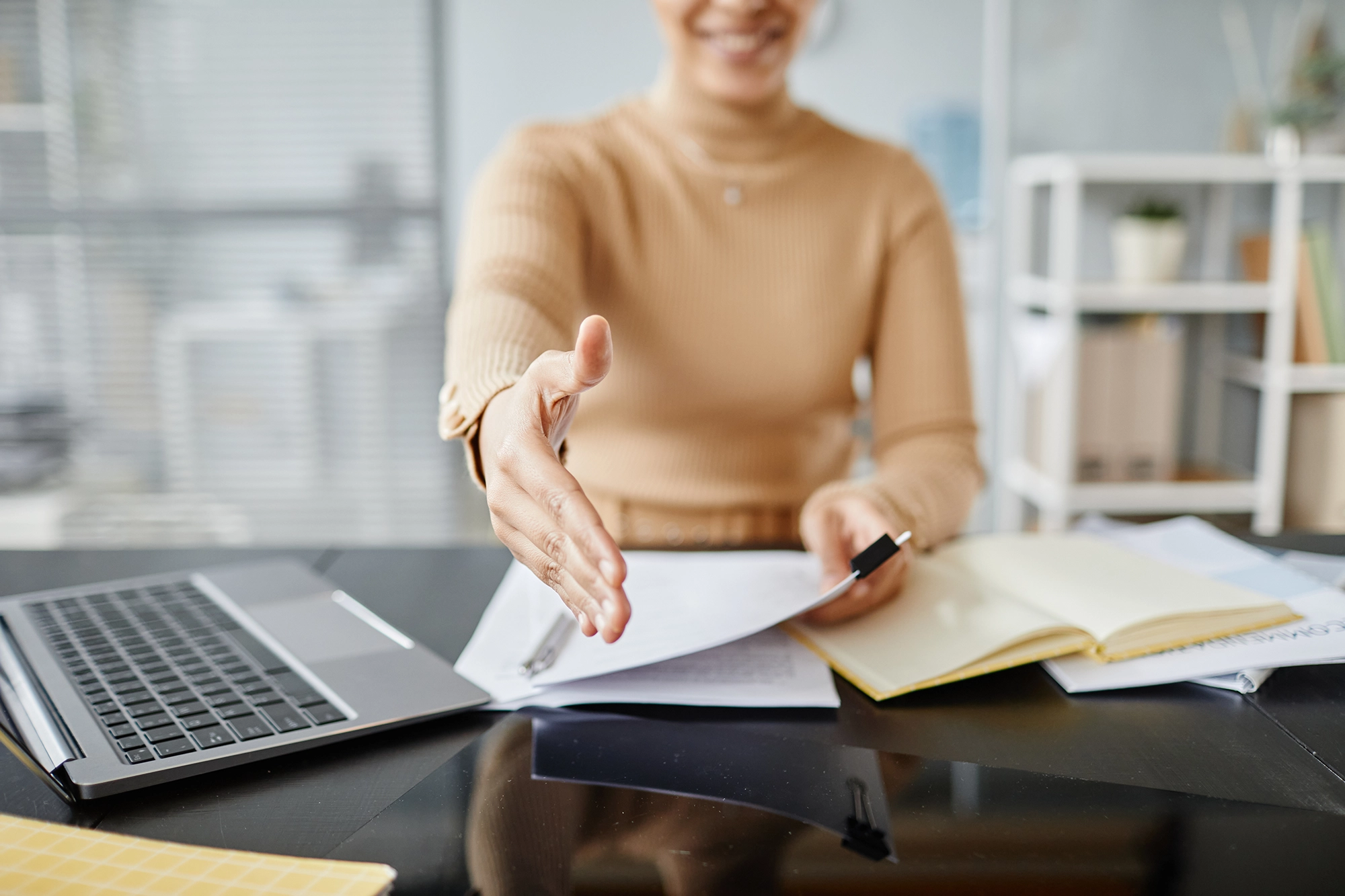 Recruiter reaching out to shake the hand of a candidate for international recruitment.