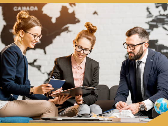 A group of international recruiters sit in a meeting together, in the background on the wall there is a map of the world.