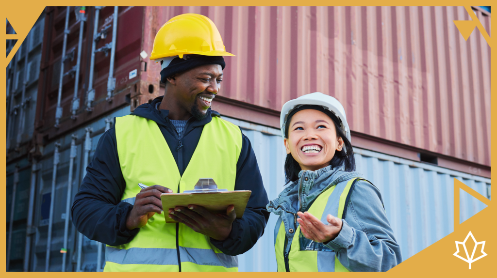 Two construction workers together wearing reflective vests and hard hats.