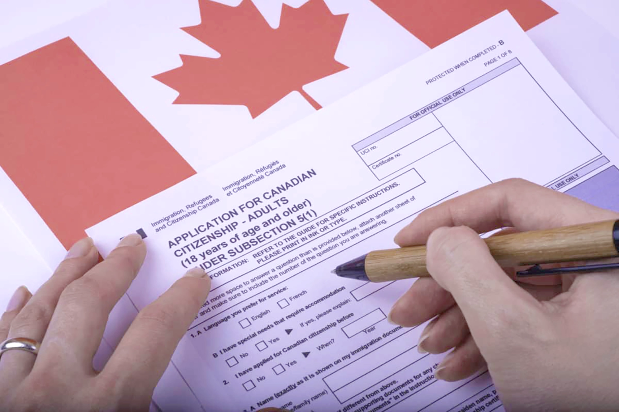 A close up of an application for Canadian citizenship next to a Canadian flag.