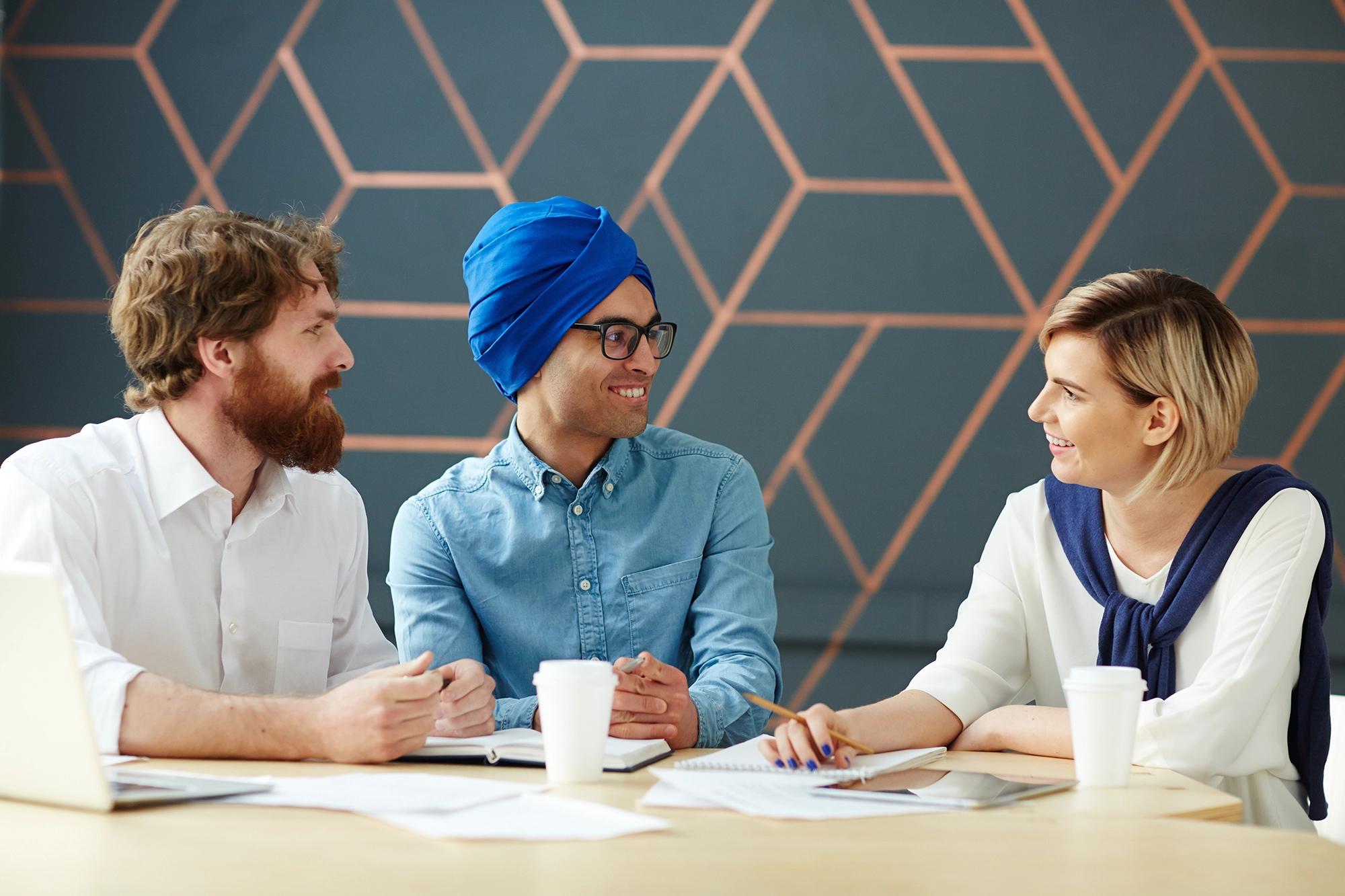 Three employees sitting together at a table for a work meeting.