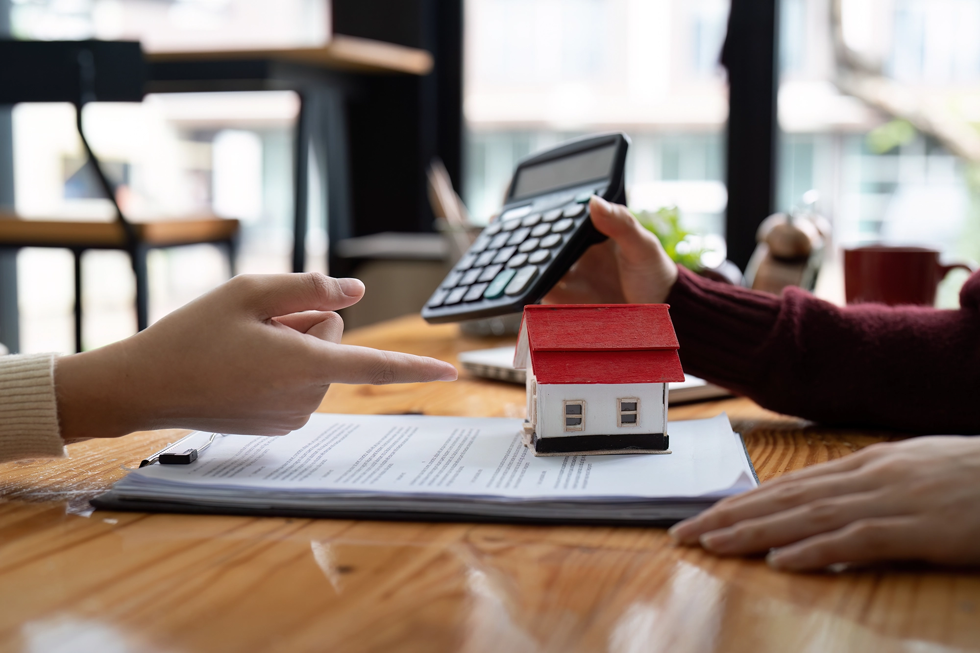 Two people sit at a desk discussing the cost of housing and accommodations for international workers, one holding a calculator.