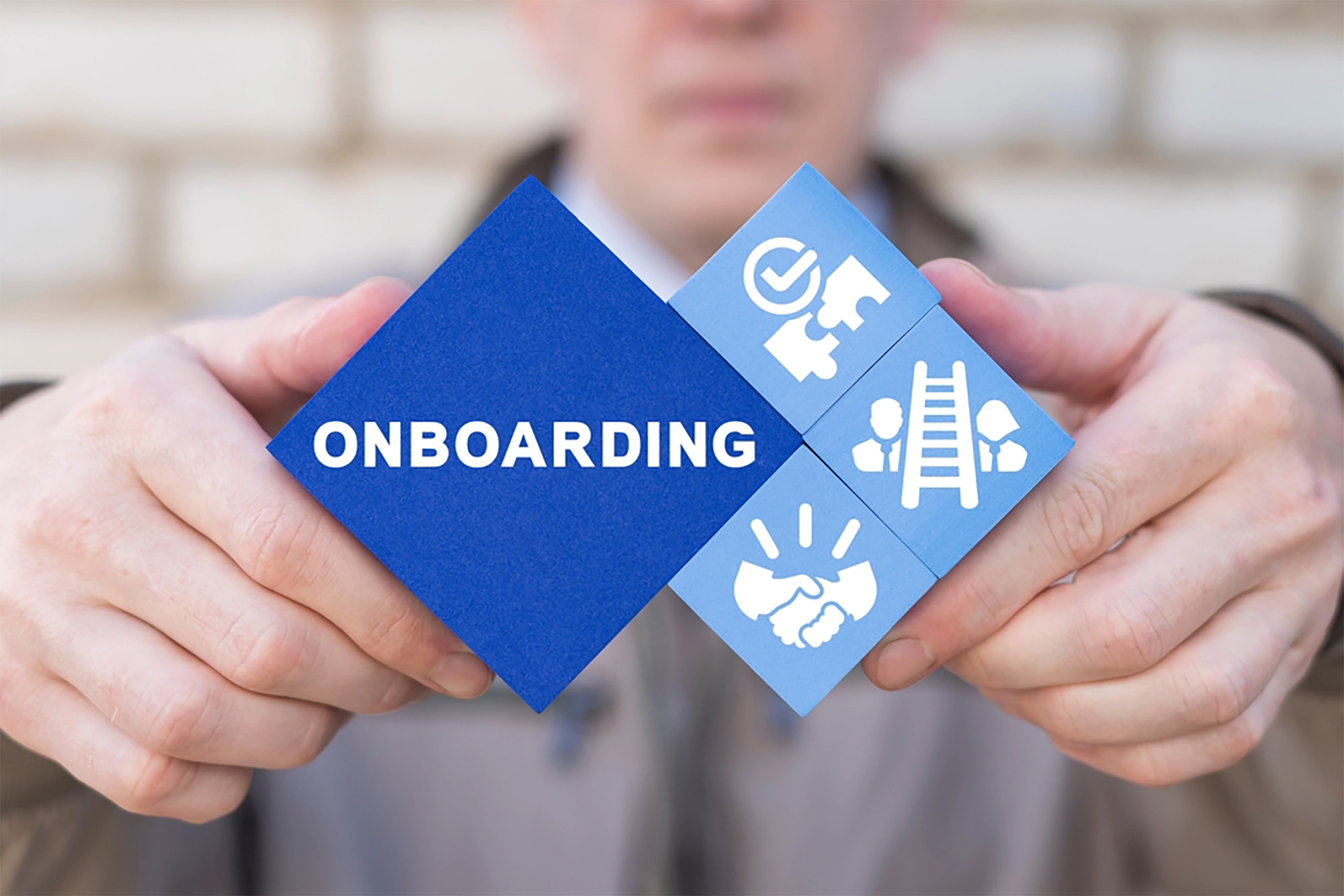 Hands holding blue cubes, one reading onboarding and the other three with onboarding-related icons.